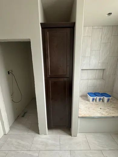 Tall linen cabinets and vanity cabinetry beside the tiled bathing area, view 2.