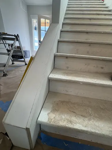 Stair-skirt fitting followed by wood handrails and black balusters on the same straight flight, view 1.