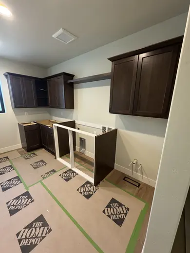 Dark wood wall cabinets, corner storage and appliance openings during installation, view 4.