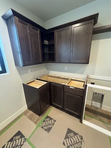 Dark wood wall cabinets, corner storage and appliance openings during installation, view 5.