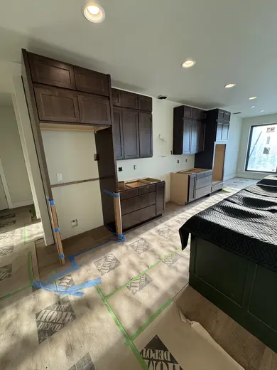Dark wood kitchen and pantry cabinetry, sliding pantry doors, a green entry bench and adjacent stair-skirt details, view 4.