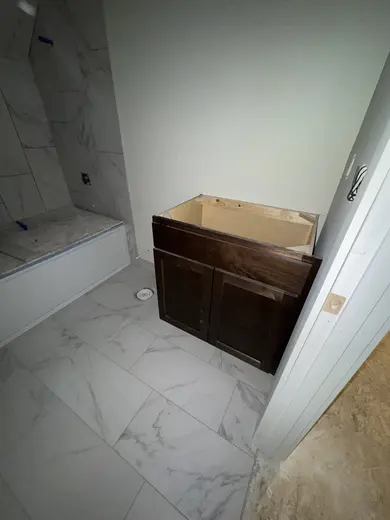 A compact wood vanity cabinet before counter installation, view 2.