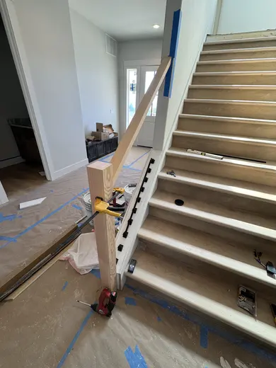 Stair-skirt fitting followed by wood handrails and black balusters on the same straight flight, view 3.