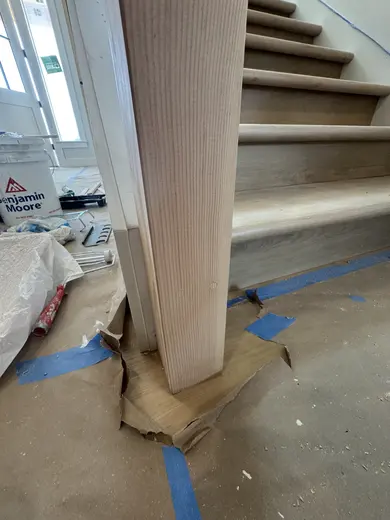 Stair-skirt fitting followed by wood handrails and black balusters on the same straight flight, view 5.