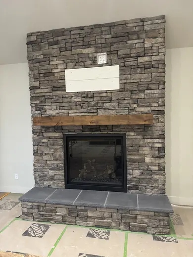 Wood ceiling beam and mantel installation in a vaulted room with a stone fireplace, view 4.