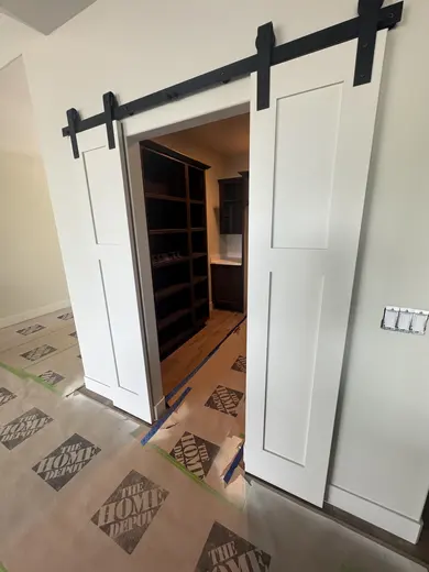 Dark wood kitchen and pantry cabinetry, sliding pantry doors, a green entry bench and adjacent stair-skirt details, view 15.