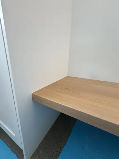 A wood seat and floating shelf in a window-side niche, view 2.