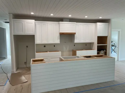 White plank ceilings, exposed wood beams, white cabinetry and a shiplap fireplace, view 7.