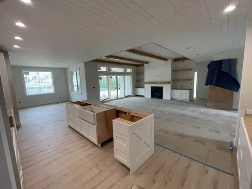 White plank ceilings, exposed wood beams, white cabinetry and a shiplap fireplace, view 8.