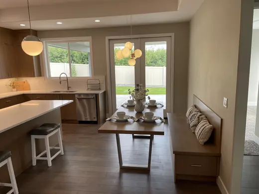 Natural-wood kitchen cabinets and a built-in dining bench beneath globe pendant lights.