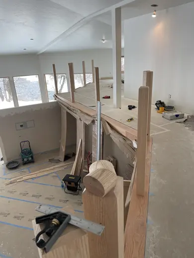 Wood railings with black balusters around a loft and the kitchen visible below, view 5.