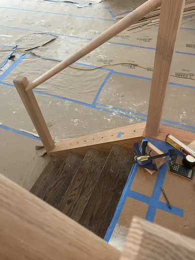 Wood railings with black balusters around a loft and the kitchen visible below, view 8.