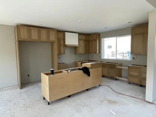 Natural wood cabinetry and a white island progressing through installation, view 1.