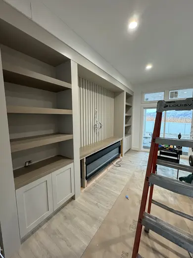 Fluted fireplace wall with side cabinets and shelves at successive installation stages, view 6.