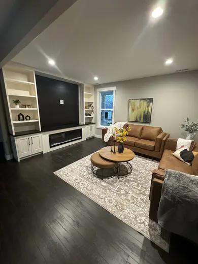 White built-in cabinets and open shelving around a dark media wall and linear fireplace.