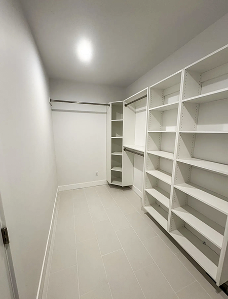 White walk-in closet with fitted shelving and hanging rails.