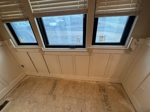 White lower-wall panel trim around a window and room corners, view 3.