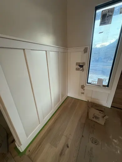 Wood entry door fitting and white lower-wall panel trim in the same entry, view 5.