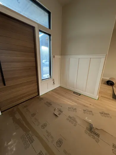 Wood entry door fitting and white lower-wall panel trim in the same entry, view 6.