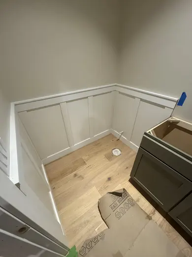 White lower-wall panel trim fitted around a vanity installation, view 1.